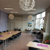 Deze lichte en flexibele ruimte is ideaal voor bijeenkomsten, workshops of maaltijden. Grote ramen zorgen voor veel daglicht, terwijl decoratieve planten en moderne lampen een warme sfeer creëren.