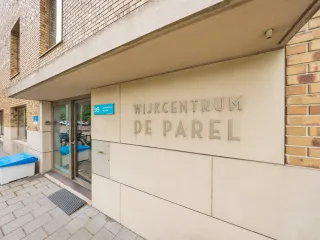 Een modern gebouw met een lichte bakstenen gevel. Een mooi entreebord naast de ingang duidt op activiteiten binnen het gebouw.