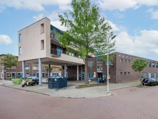 De Wippolder in Delft is een eigentijds ogend, laagbouwpand met een robuuste bakstenen gevel, waarbij de entree subtiel is benadrukt met een overstekend dakje en grote glaspuien die uitnodigend uitzicht bieden op de omliggende groenrijke pleinruimte.