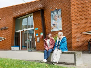 Twee dames die gezellig voor het wijkcentrum zitten te praten