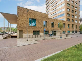 Een modern gebouw met een lichte bakstenen gevel. Een mooi entreebord naast de ingang duidt op activiteiten binnen het gebouw.