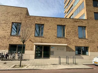 Een opvallend, modern wijkgebouw met een gele baksteenstructuur.