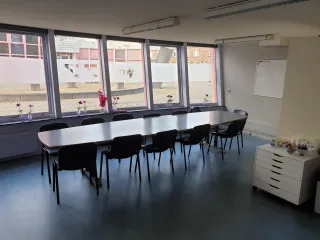 Deze vergaderruimte biedt plaats aan een groep deelnemers en heeft een frisse uitstraling dankzij de grote ramen. Ideaal voor zakelijke bijeenkomsten of trainingen.
