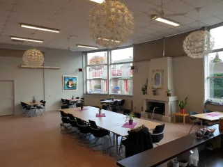 Deze lichte en flexibele ruimte is ideaal voor bijeenkomsten, workshops of maaltijden. Grote ramen zorgen voor veel daglicht, terwijl decoratieve planten en moderne lampen een warme sfeer creëren.