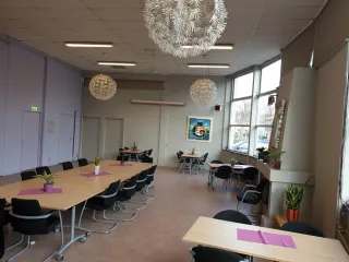 Deze lichte en flexibele ruimte is ideaal voor bijeenkomsten, workshops of maaltijden. Grote ramen zorgen voor veel daglicht, terwijl decoratieve planten en moderne lampen een warme sfeer creëren.